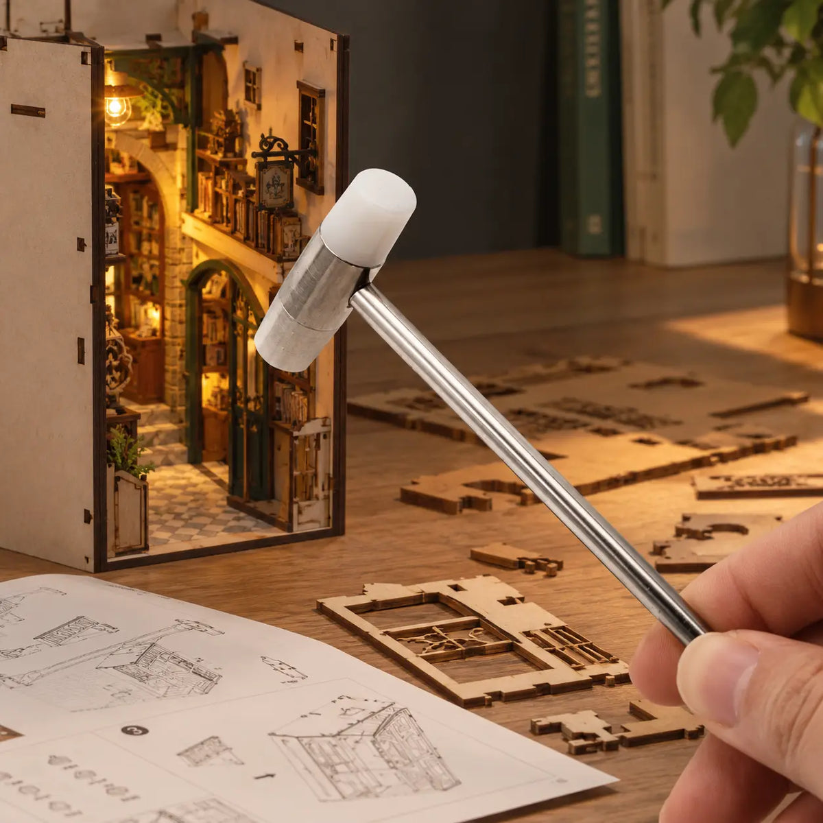 Mini marteau utilisé pour monter un book nook, pièces en bois et notice sur la table